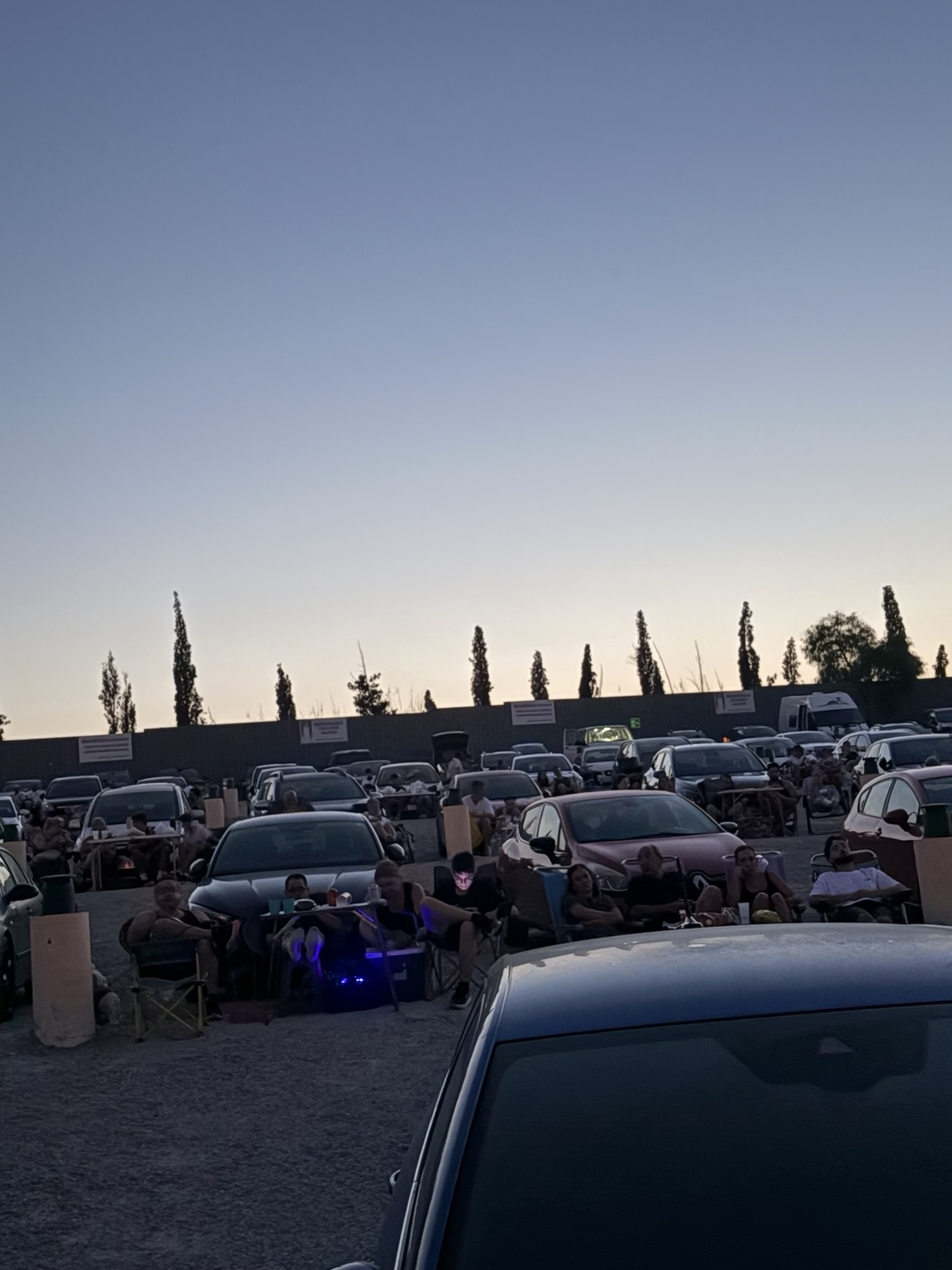 Espectadores preparan sillas y mesas junto a sus vehículos en Autocine El Sur